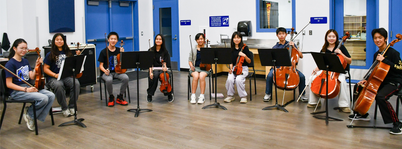 A group of students playing string instruments in a music room.