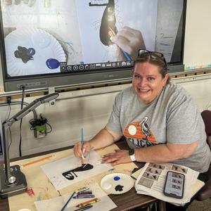 Volunteer Smiling and Painting a Bird