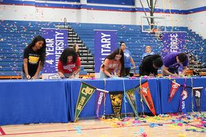 Students celebrating with confetti at a signing event for universities.
