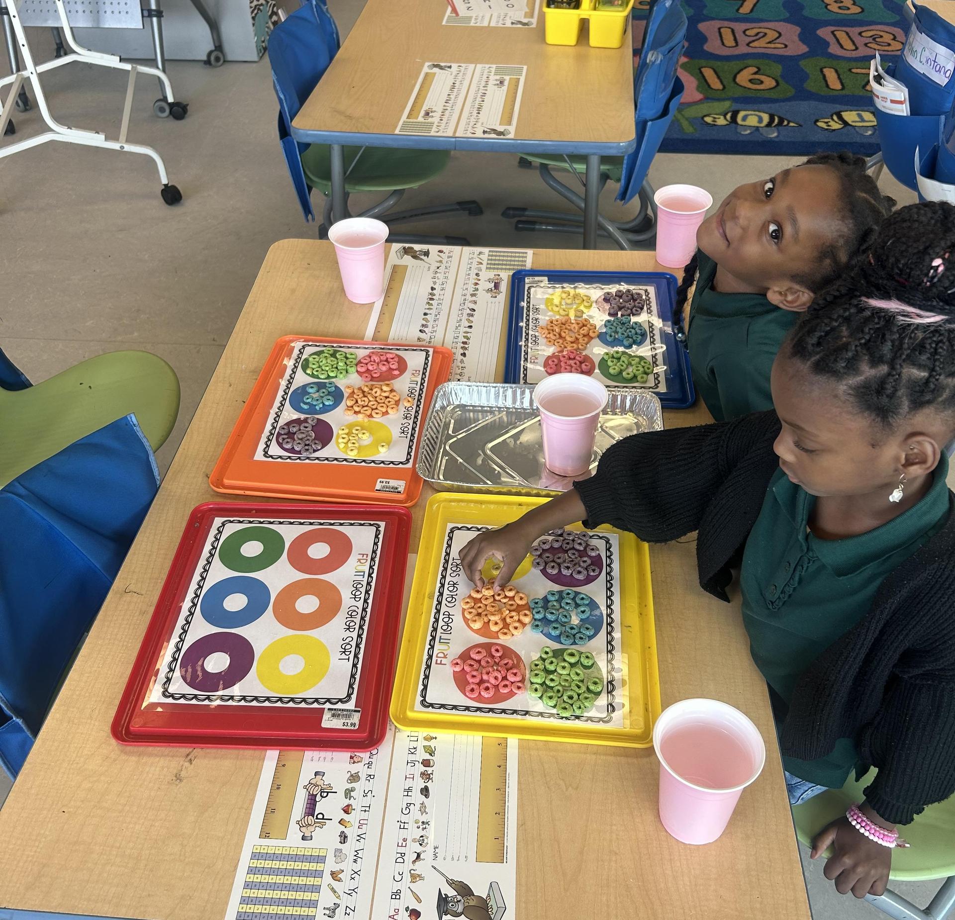 Two children at a table engaged in a colorful sorting activity.