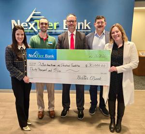 NexTier employees holding a giant check making a donation.