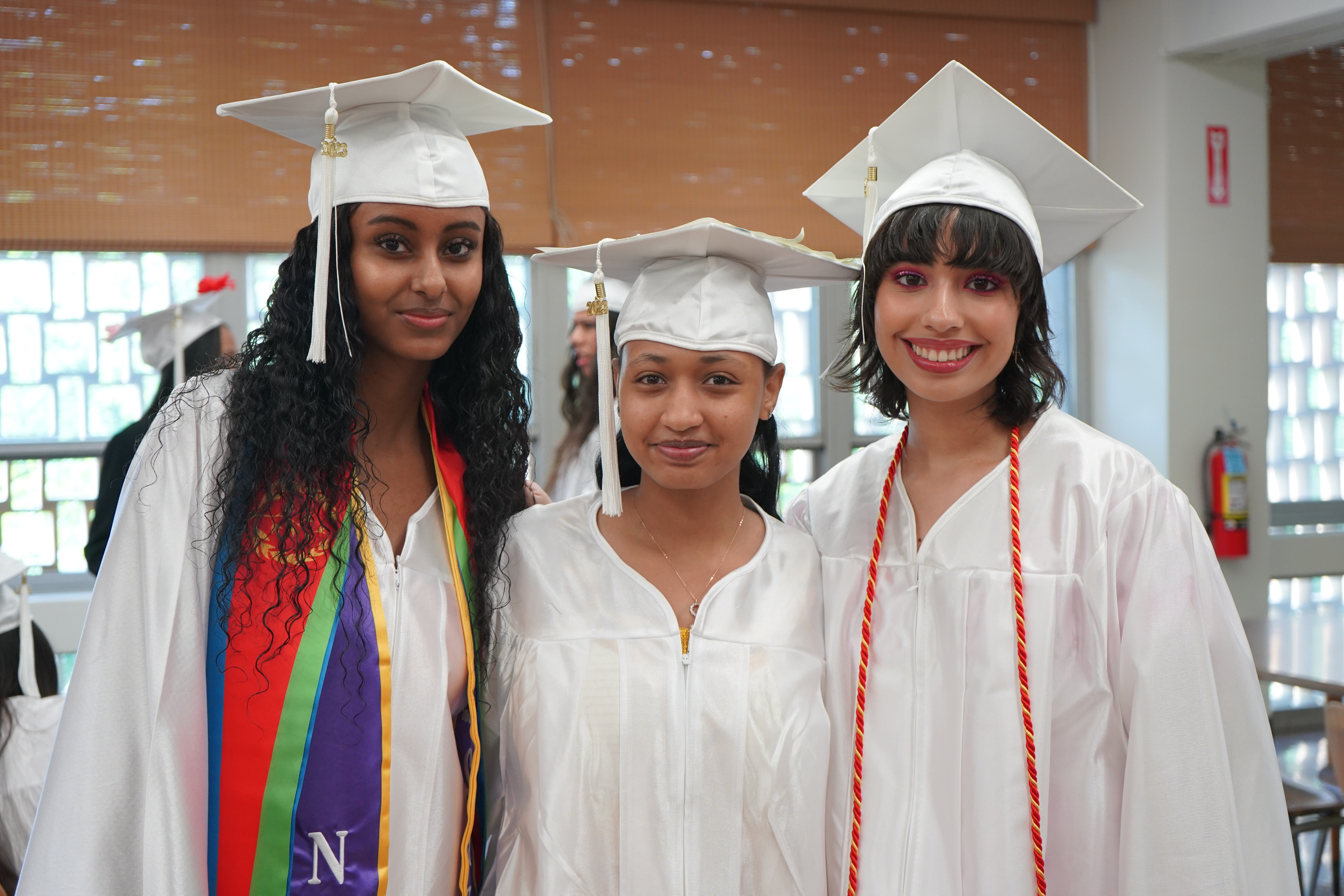 3 students posing in a white cap and gown