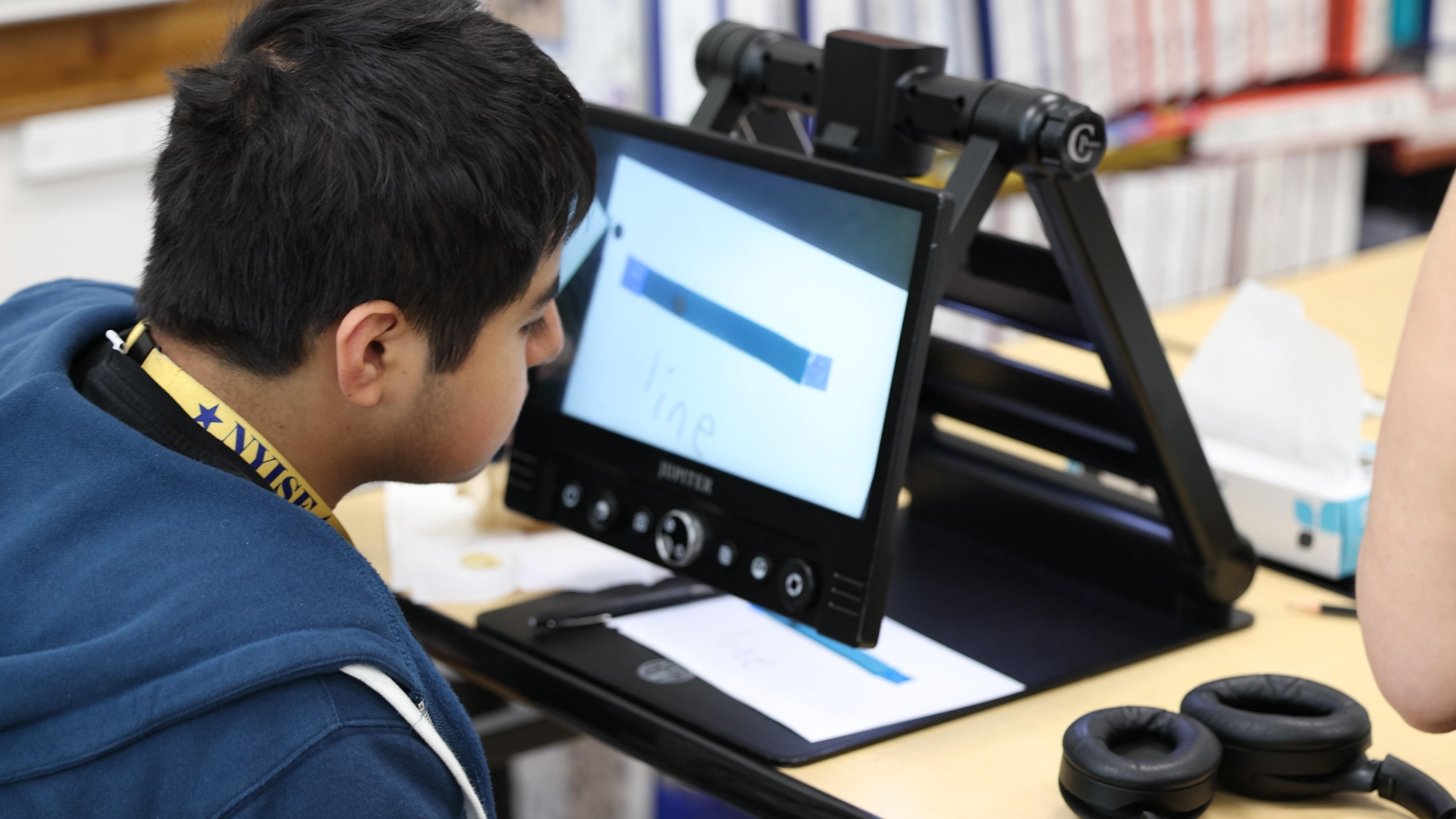 a boy leans in to a magnifying screen reader