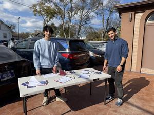 Nashville School of Excellence volunteer collecting parent interest forms during a community outreach event.