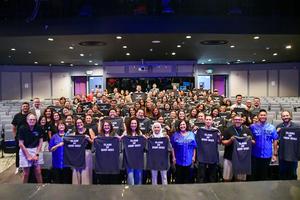 New employees pose for a photo holding “Class of 2026-2027” shirts in the Diamond Bar High School Performing Arts Center.