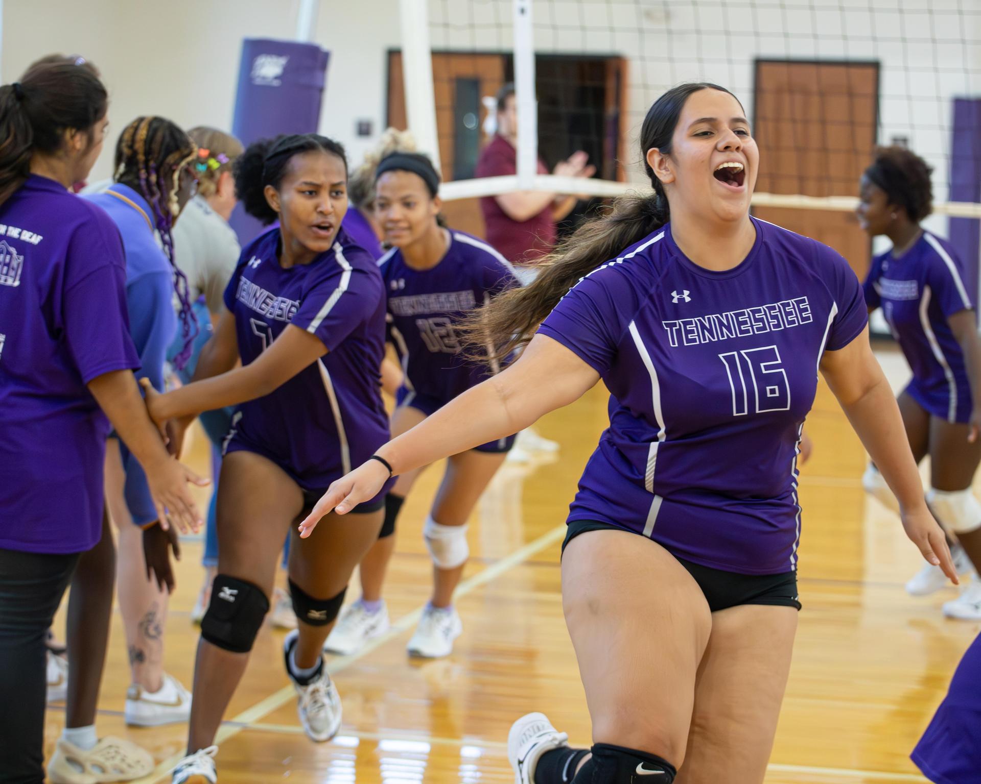 Player joyfully running past teammates after a play, showcasing team spirit.
