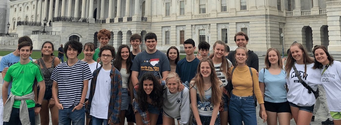 A photo of a group of students on a field trip with buildings in the background