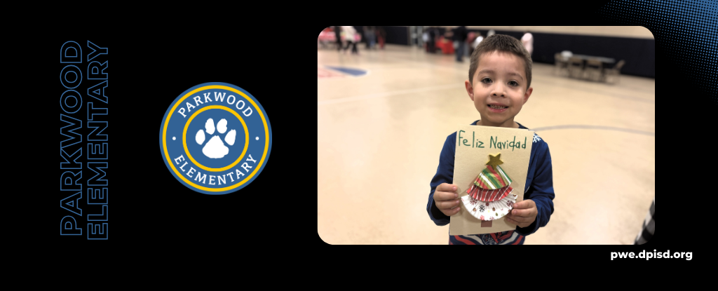 A boy holding a decorated card for Feliz Navidad in a gymnasium.
