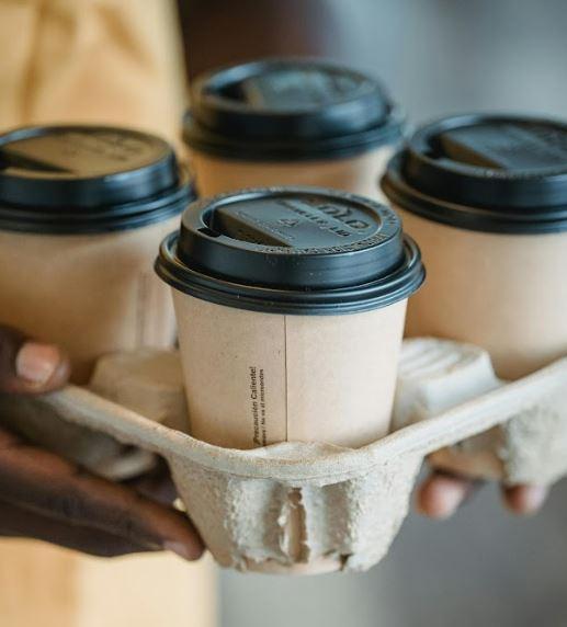 Four paper cups of hot coffee in a carrier