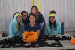 Students in costume with a pumpkin bucket filled with treats