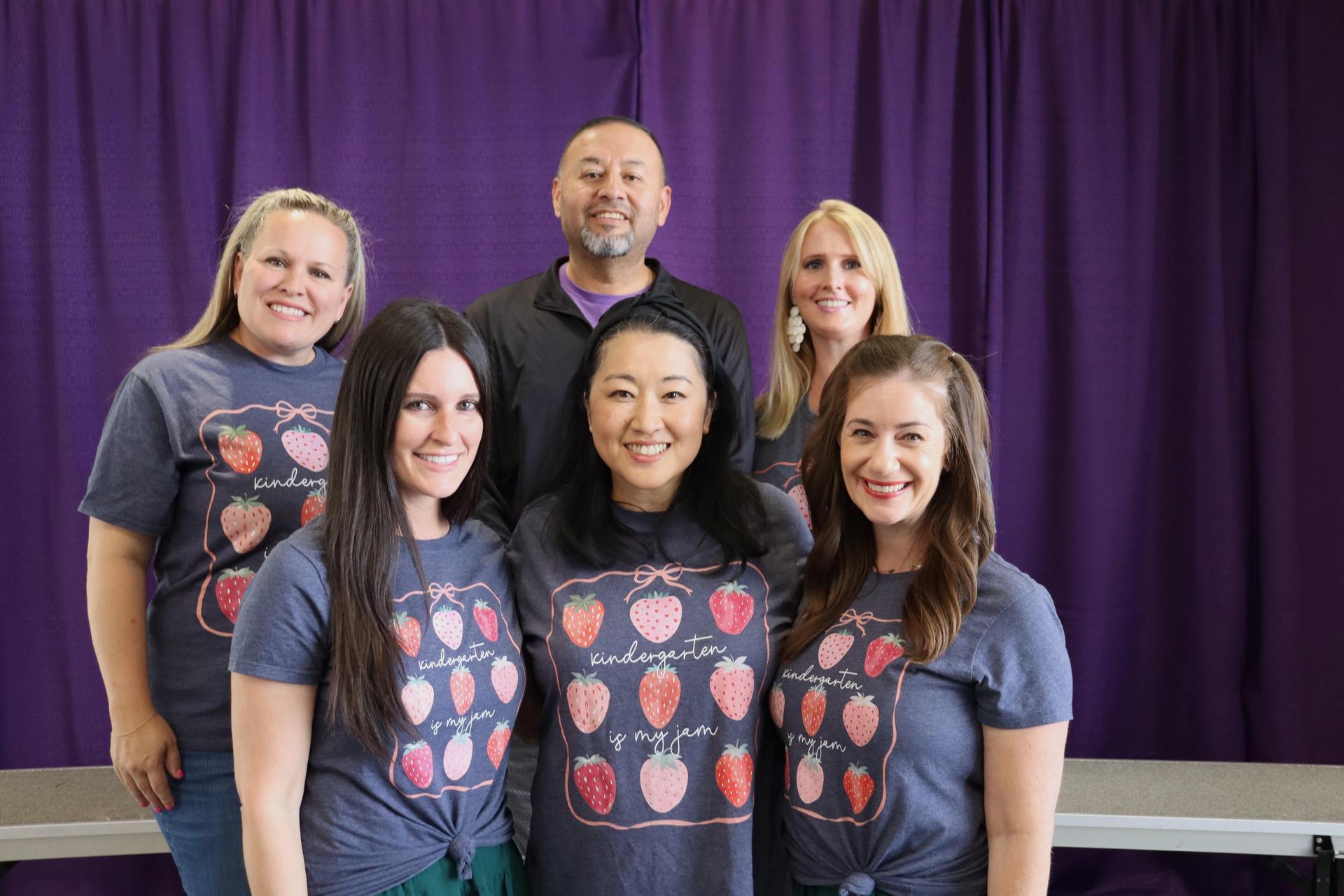 The Kindergarten teachers in matching t-shirts, smiling together with a Stargate purple background.