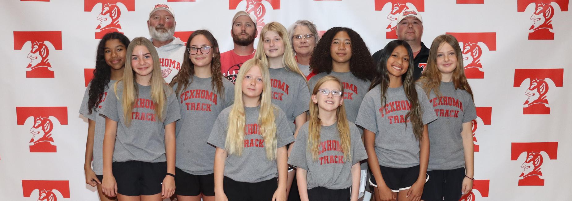 Group of young girls in gray shirts posing for a team photo.