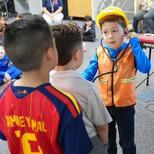 student dressed as a builder listens to heartbeat of classmate