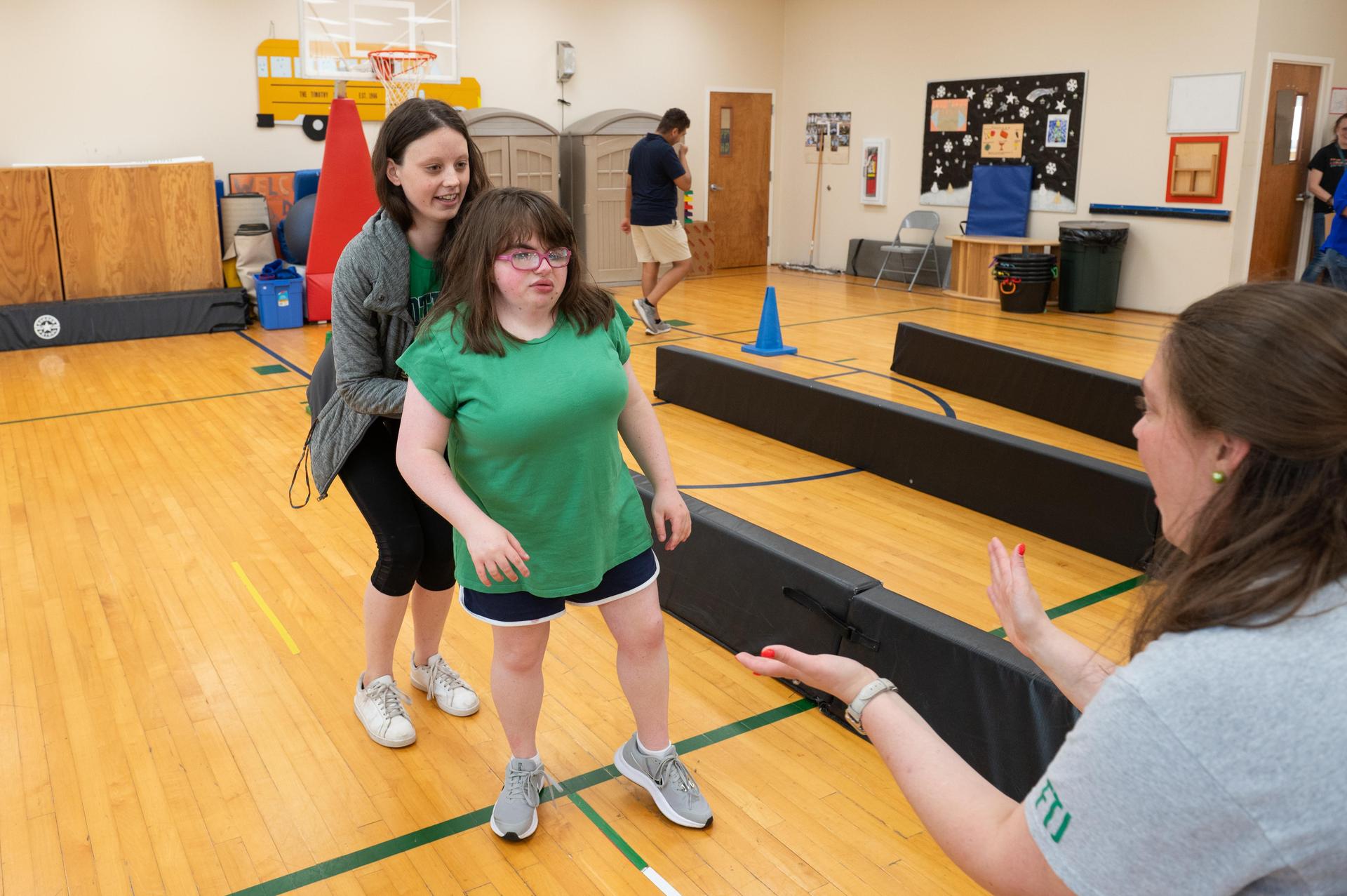 Teacher helping student walk towards other teacher.