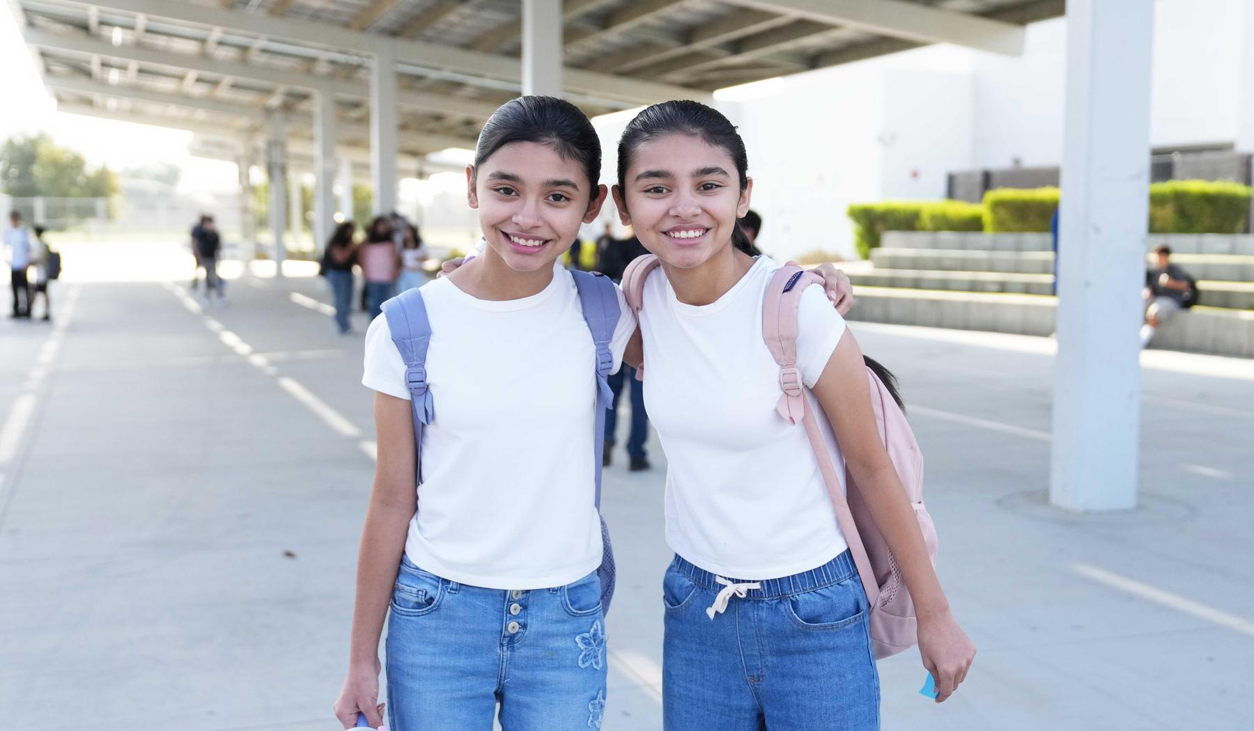 two girls in white shirts and jeans standing under solar panels at MVMS