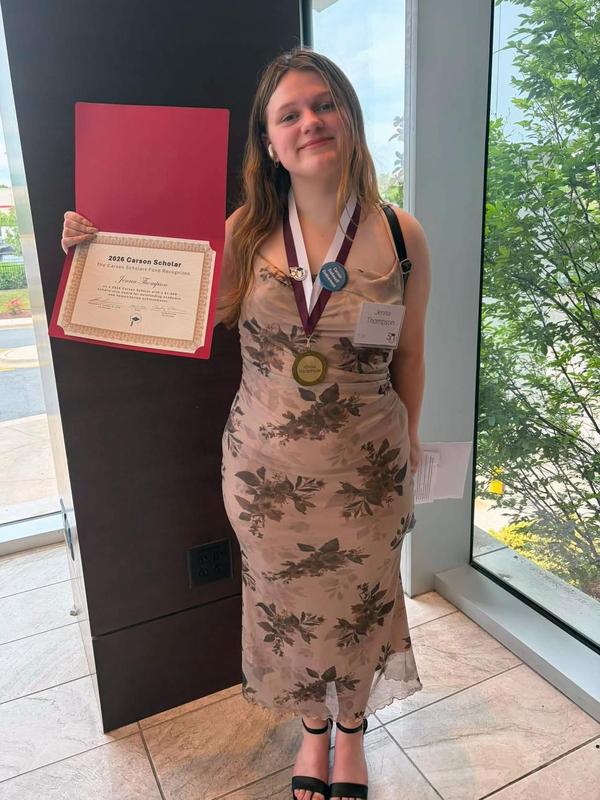 Penn Yan Academy student Jenna Thompson smiles while holding a certificate and wearing a medal.