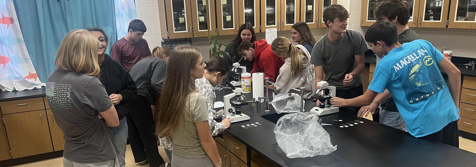 Students engaged in a science lab, using microscopes and working collaboratively.