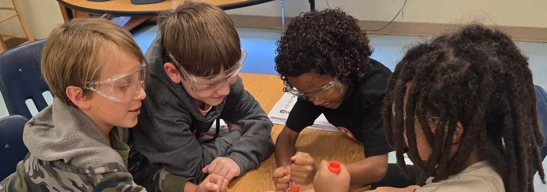 Kids collaborating on a science project at a table with lab materials.