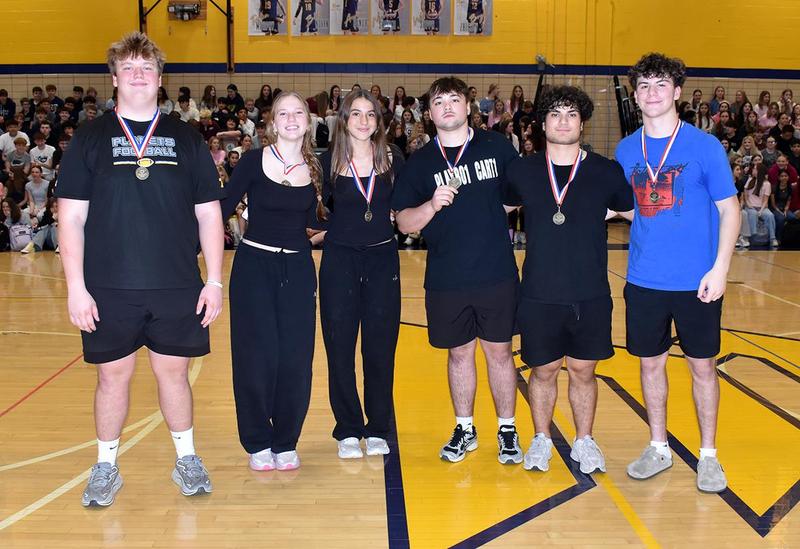 a group of six high school students wearing black woith gold medal necklaces