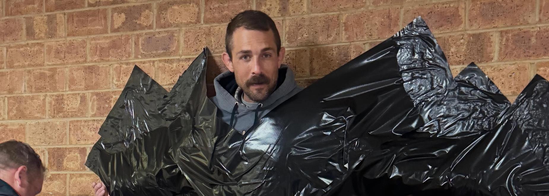 Person applying black tape to a textured wall.