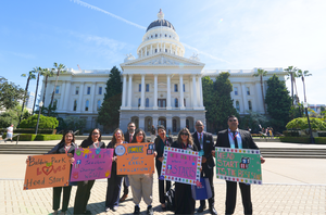 The ECE team and parents poses for a photo in front of the state capital building with their advocacy posters.