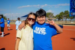 Two student smiling for a picture with arms around each other at field day.
