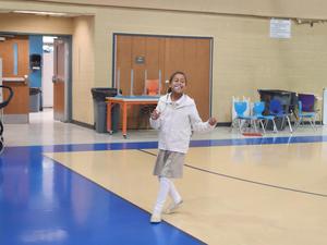 A girl balances a pom pom using a spoon.