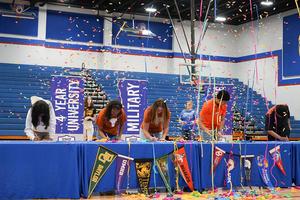 Students celebrate with confetti as they sign commitment letters at a signing event.