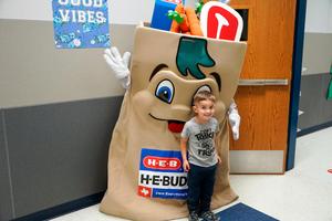 HEB Buddy Mascot with Legacy Student Smiling