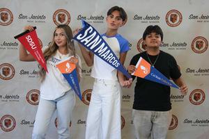 three students holding college pennants