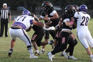 Football players in black and white uniforms competing on a grassy field.