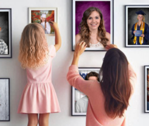Mother and daughter in pink hanging school photos on a white wall