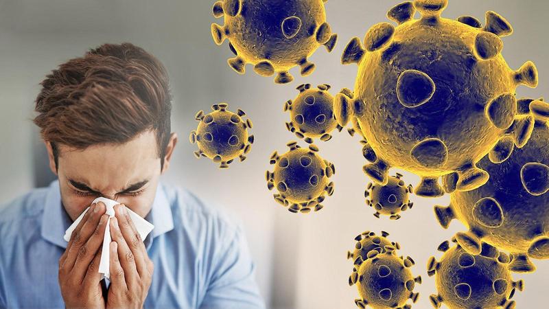 Image of man blowing his nose with image of coronavirus in the background