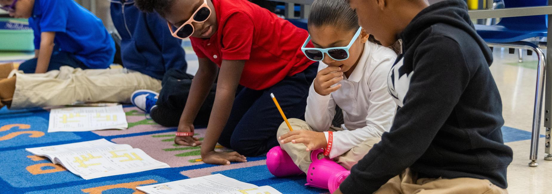 Students wear sunglasses while working on a worksheet