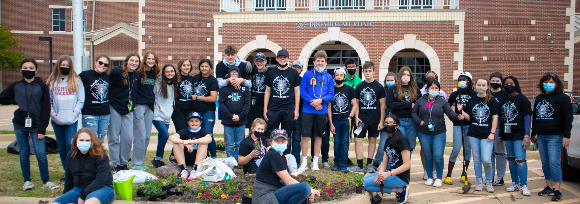 large group of teens outside of campus after planting spring flowers