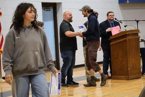Carpentry graduate walks to her seat after receiving her certificate