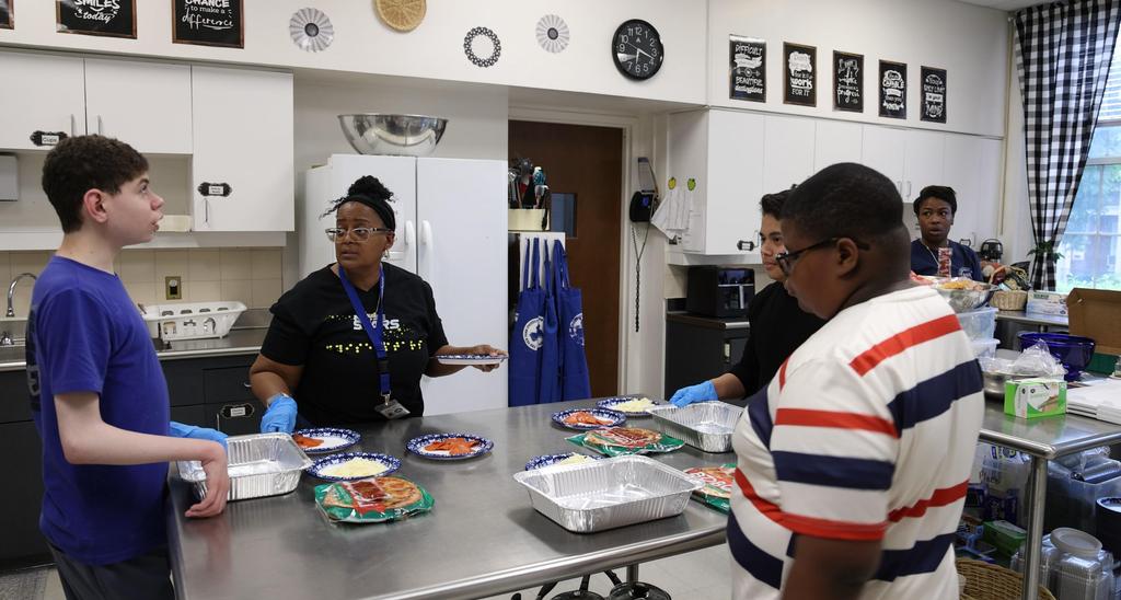 A group of people preparing food in a kitchen with plates and trays.