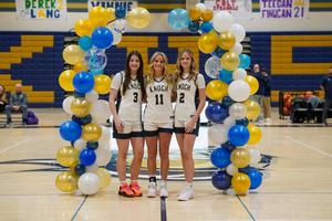 three girl basketball players under a balloon arch