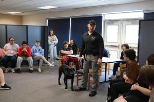 police officer and k9 officer talking to a group of students who are sitting down