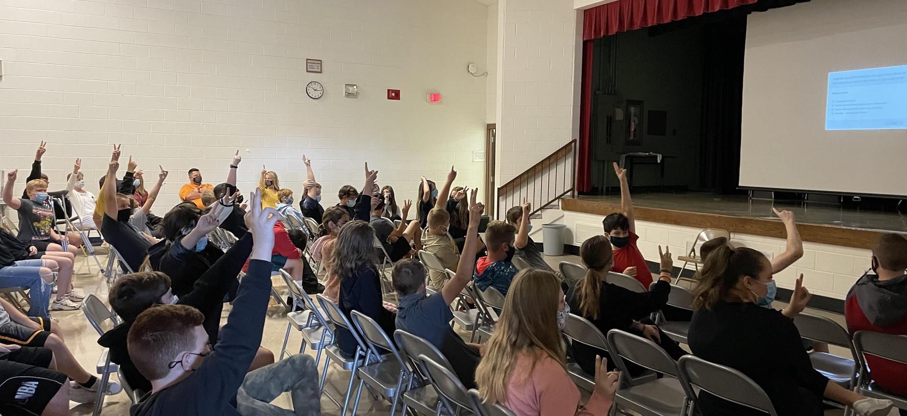 Students watch a video in an auditorium.