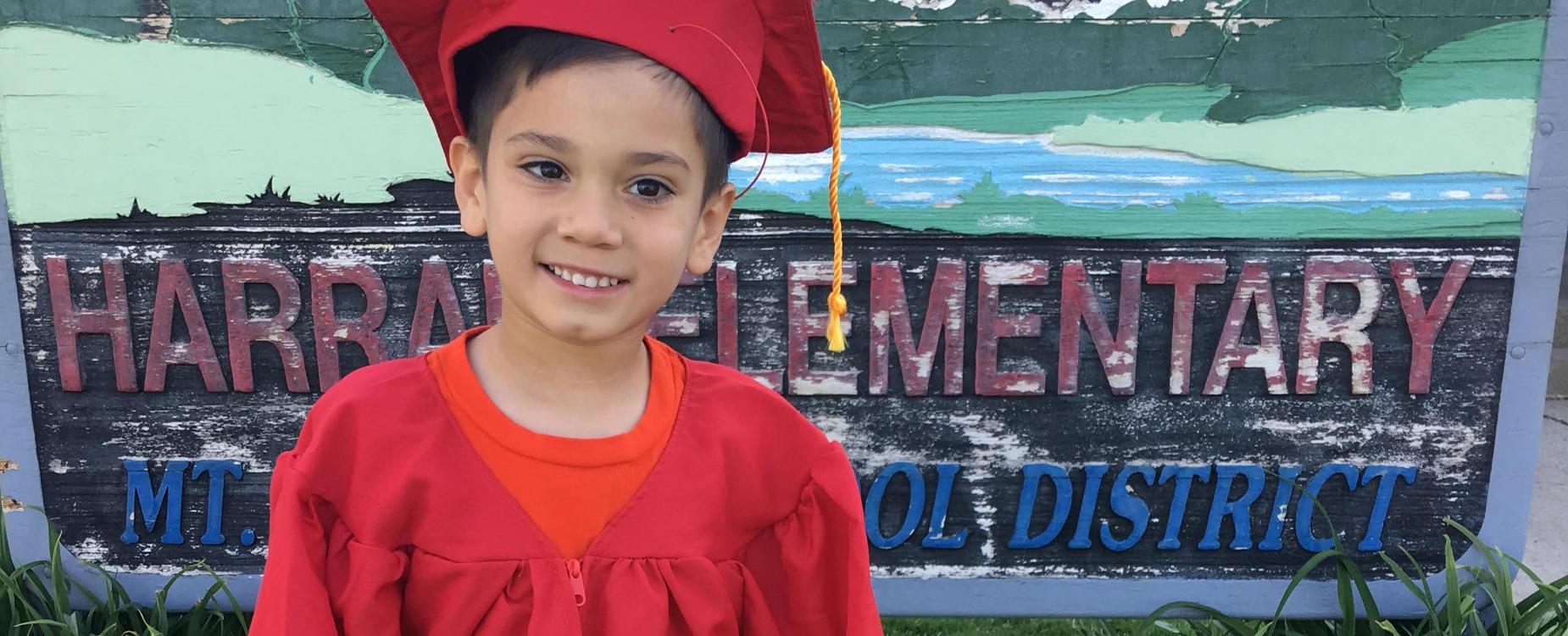 Student in front of Harrah Elementary sign