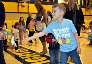 Boy in a light blue shirt extends his arm while participating in an event with friends.