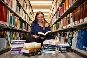 Woods sitting with a pile of books at the library 2026
