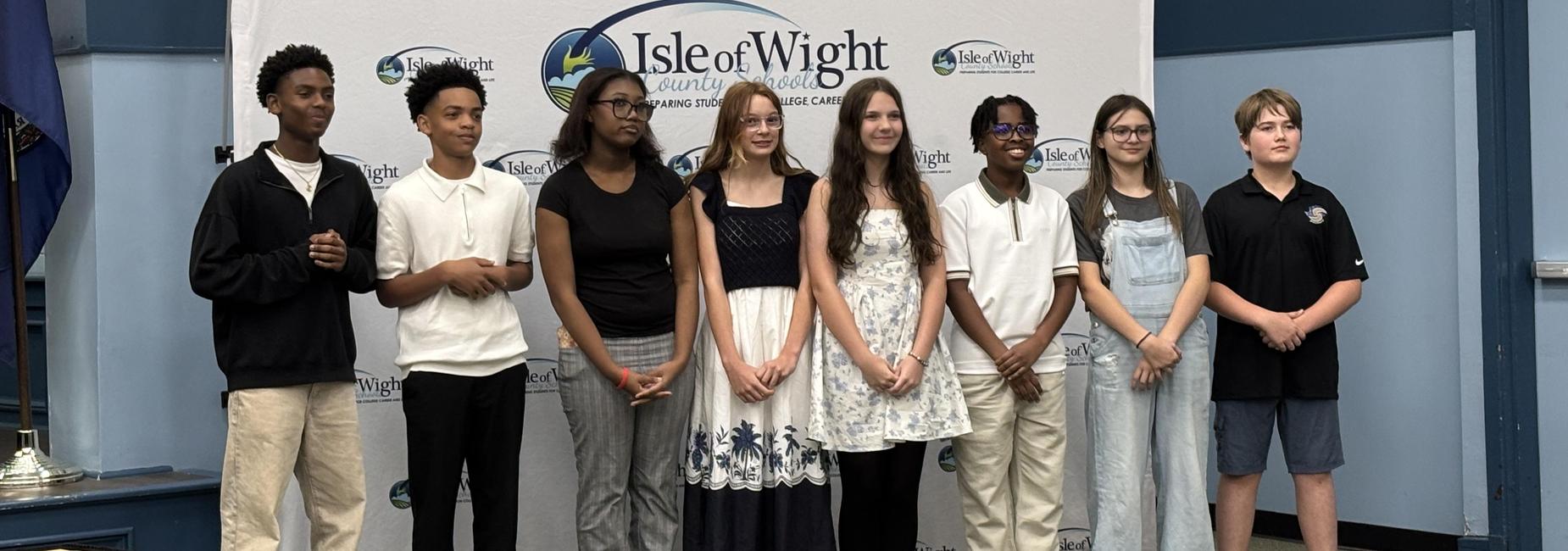 Group of eight young people posing together in a formal setting.