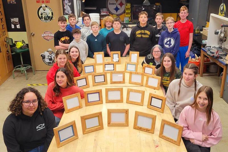 Some of the seventh-grade students gather around the frames they built in Mr. Kymer’s class