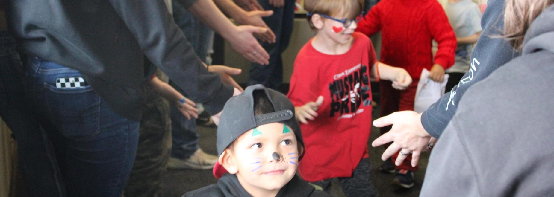 Children in costumes participate in a lively celebration, with face paint and smiles.