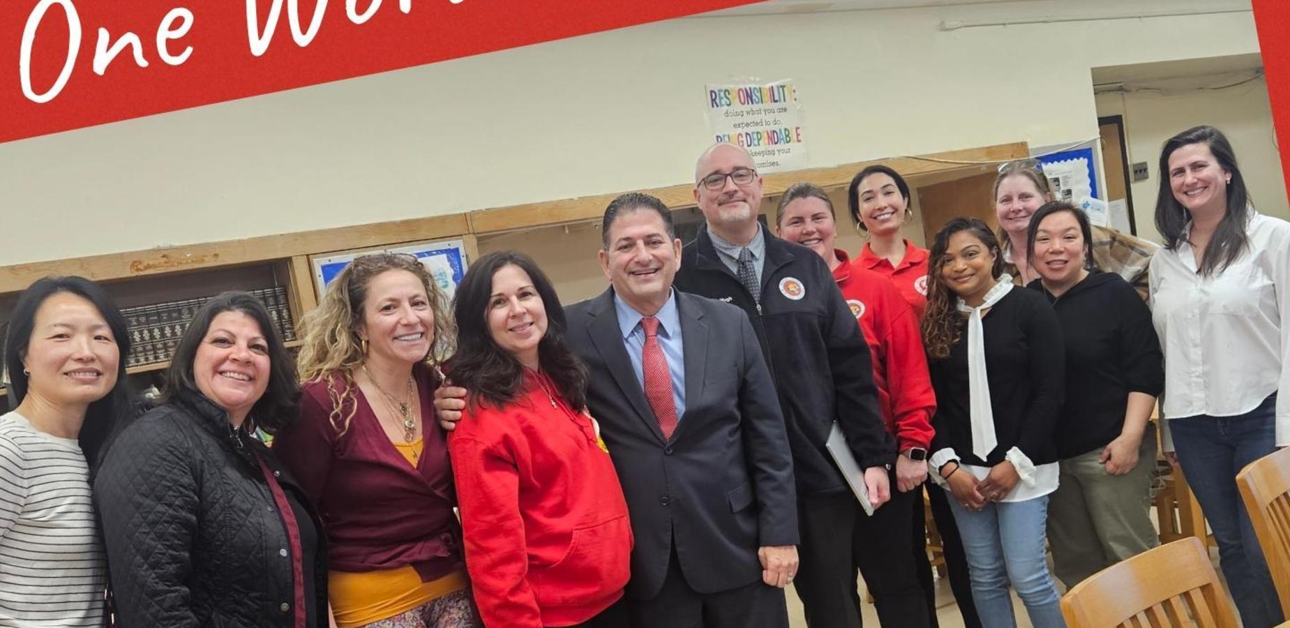 Group of diverse individuals smiling and posing together in a school setting.