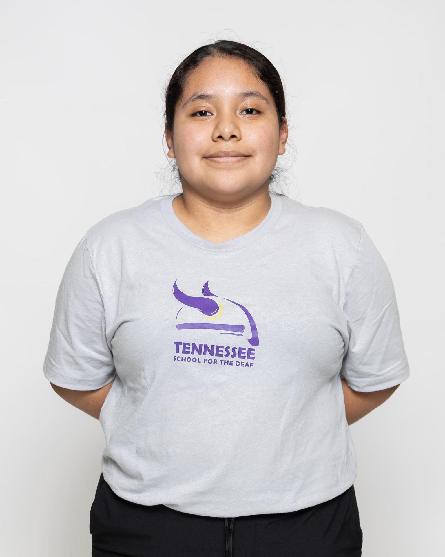 Another youth in a gray t-shirt with Tennessee School for the Deaf logo, hands behind back.