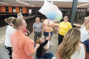 A team of teachers work to keep a bag of balloons in the air.