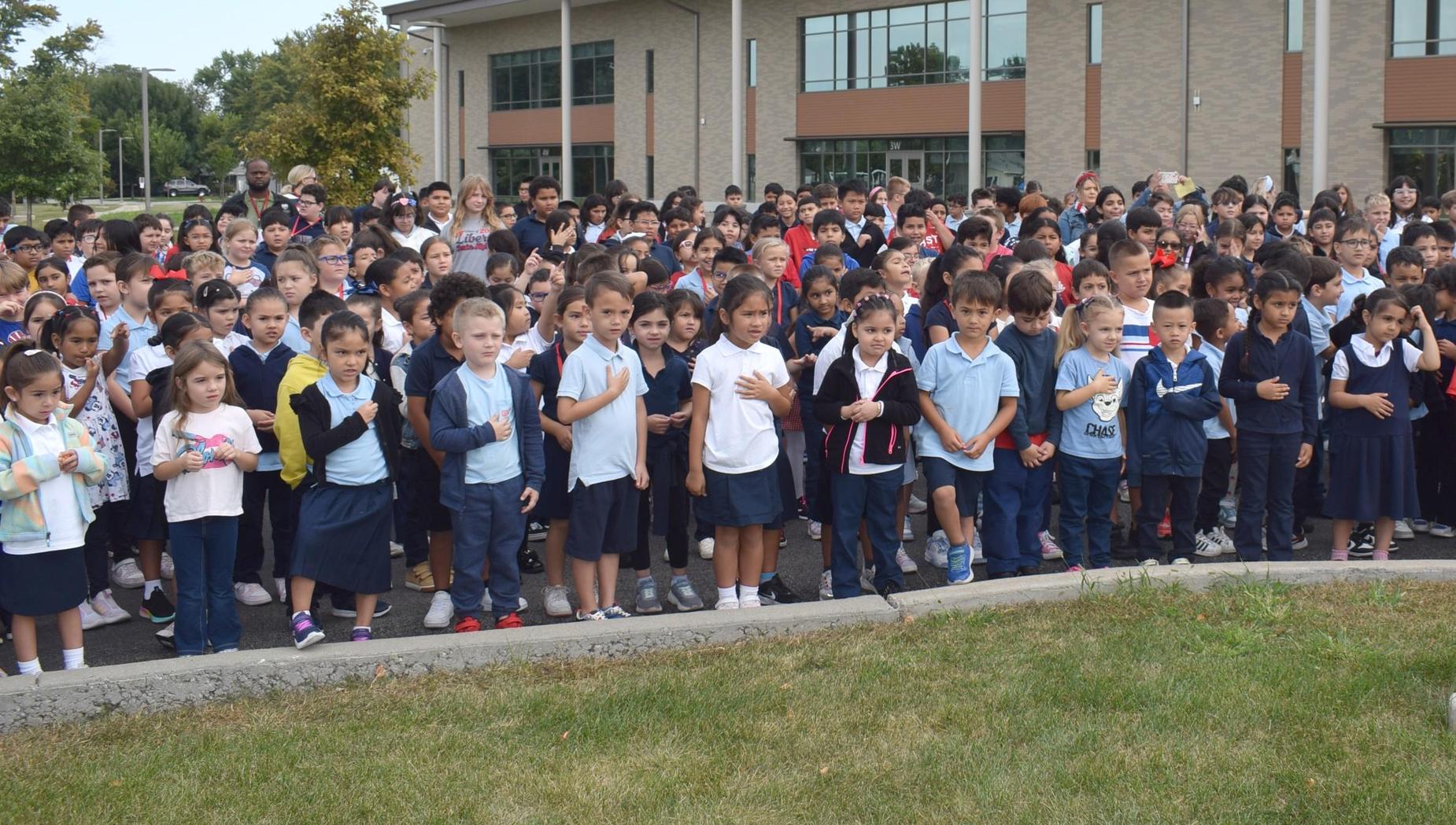 A crowd of diverse students gathering outside a school for an event.